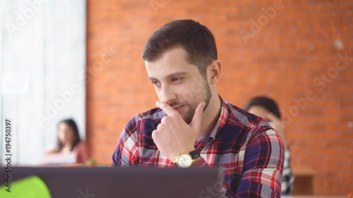 cheerful energetic Young man sitting opposite the computer. Long working day. in the background, people are crowded. 4k