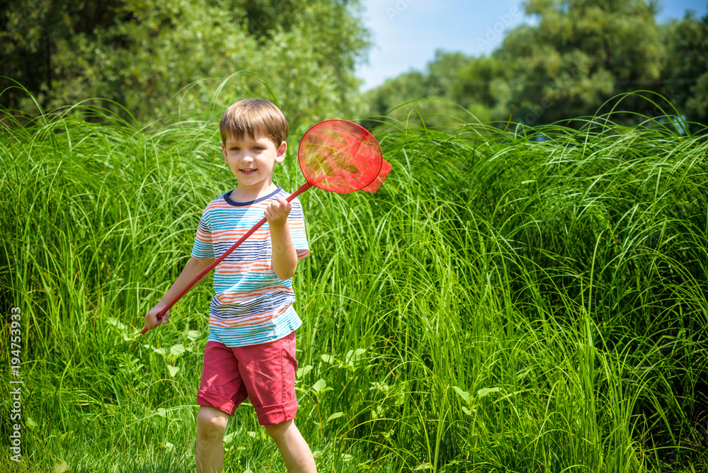 Adorable Caucasian kid playing with scoop-net on the meadow on warm and sunny summer or spring day. Adorable Caucasian kid playing with scoop-net on the meadow on warm and sunny summer or spring day.