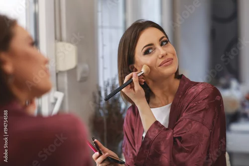 Obraz Young woman applying makeup on face at home
