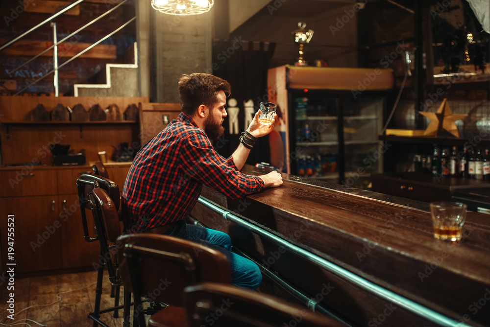 Man sitting at the bar counter and drink alcohol - obrazy, fototapety, plakaty 