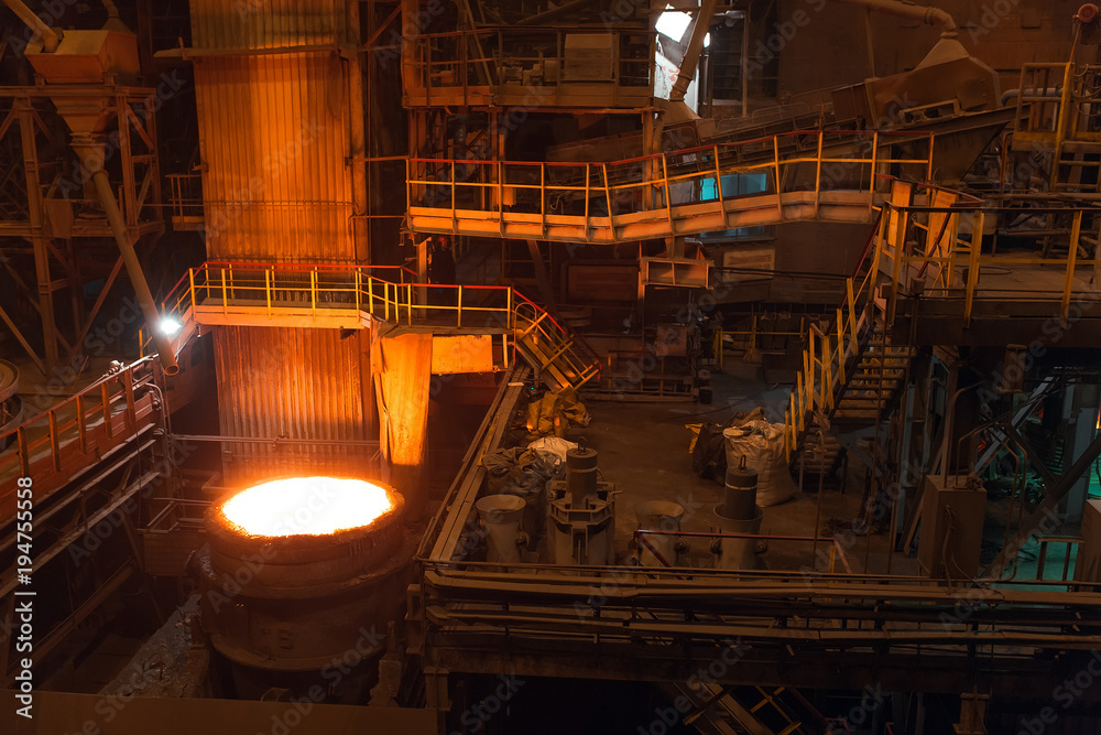 Melting of metal in a steel plant. High temperature in the melting furnace. Metallurgical industry. Factory for the manufacture of metal pipes. Bucket for feeding metal into molds.