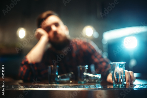 Drunk man sleeps at bar counter, alcohol addiction