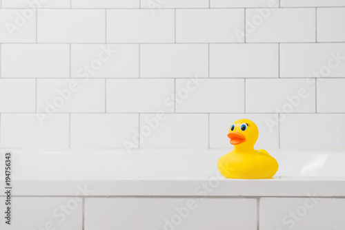 Toy yellow duck in the bathroom on a light brick background