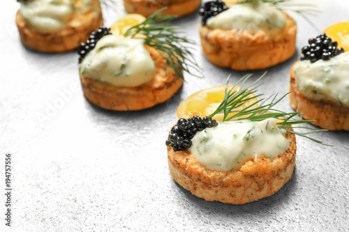 Delicious canapes with black caviar on metal background