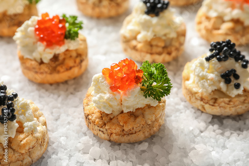 Delicious canapes with black and red caviar on sea salt