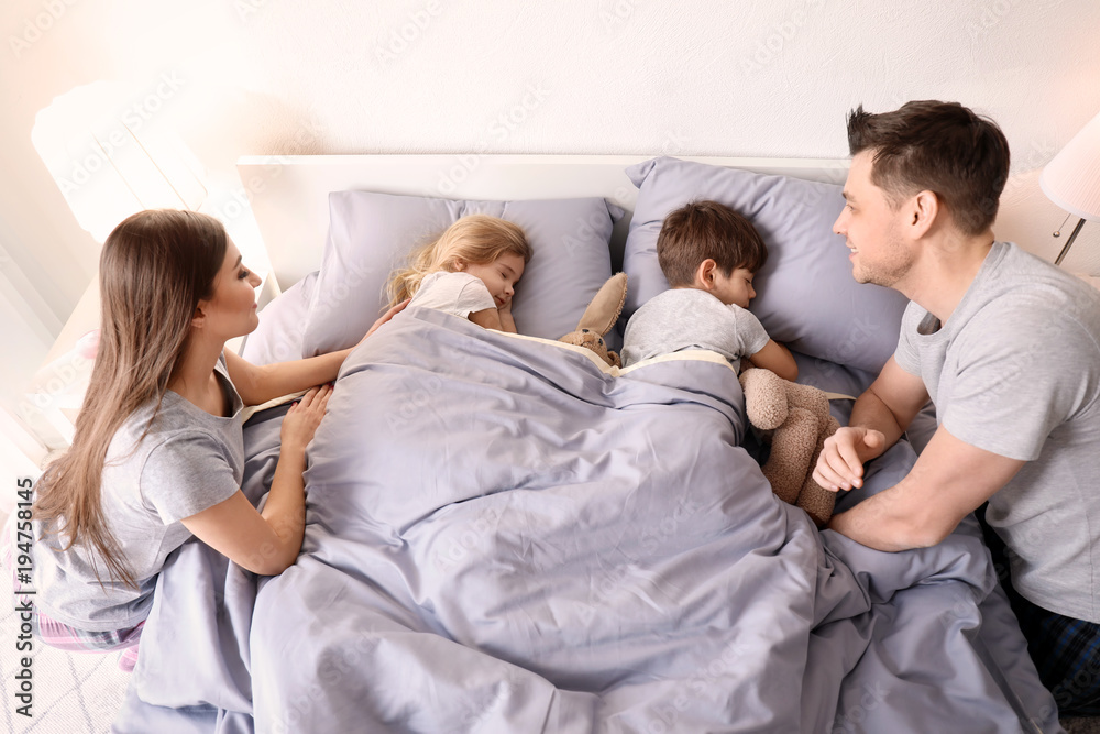 Obraz premium Parents getting little children to bed at home. Family bedtime