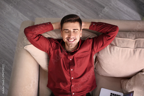 Young man resting on sofa a...