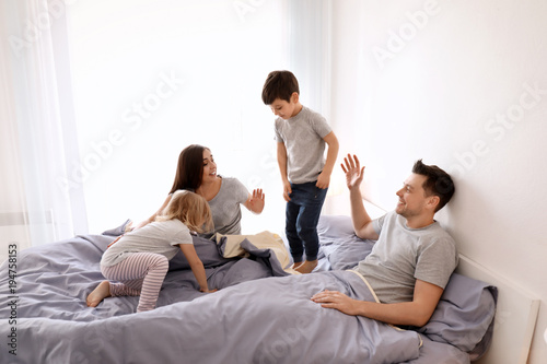 Cute children with parents having fun on bed together at home