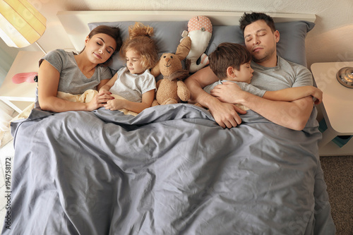 Family sleeping in bed at home