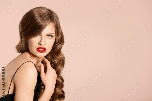 Beautiful young woman with long wavy hair on light background
