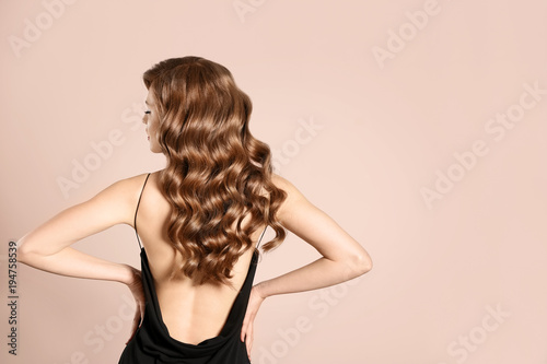 Beautiful young woman with long wavy hair on light background photo