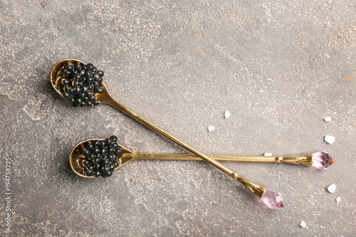 Spoons with delicious black caviar on grey background