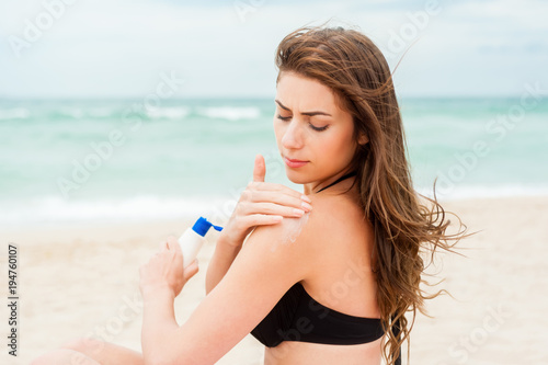 Woman moisturizing applying sun cream on her tanned body 