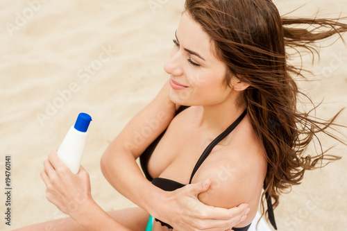 Woman moisturizing applying sun cream on her tanned body 