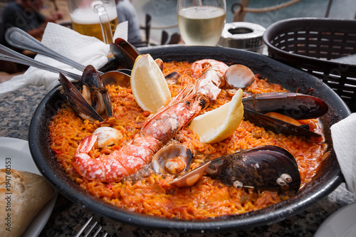 Frying pan with fresh Spanish paella is on the restaurant table. Close up.