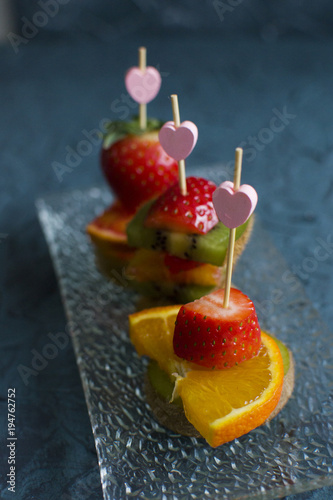several fruit canapés with strawberry, kiwi, orange on the glass plate