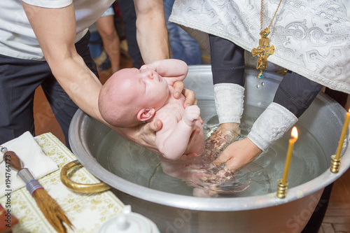 Abbe blessing a little infant kid in baptism (christening) ceremony in church, bathing him