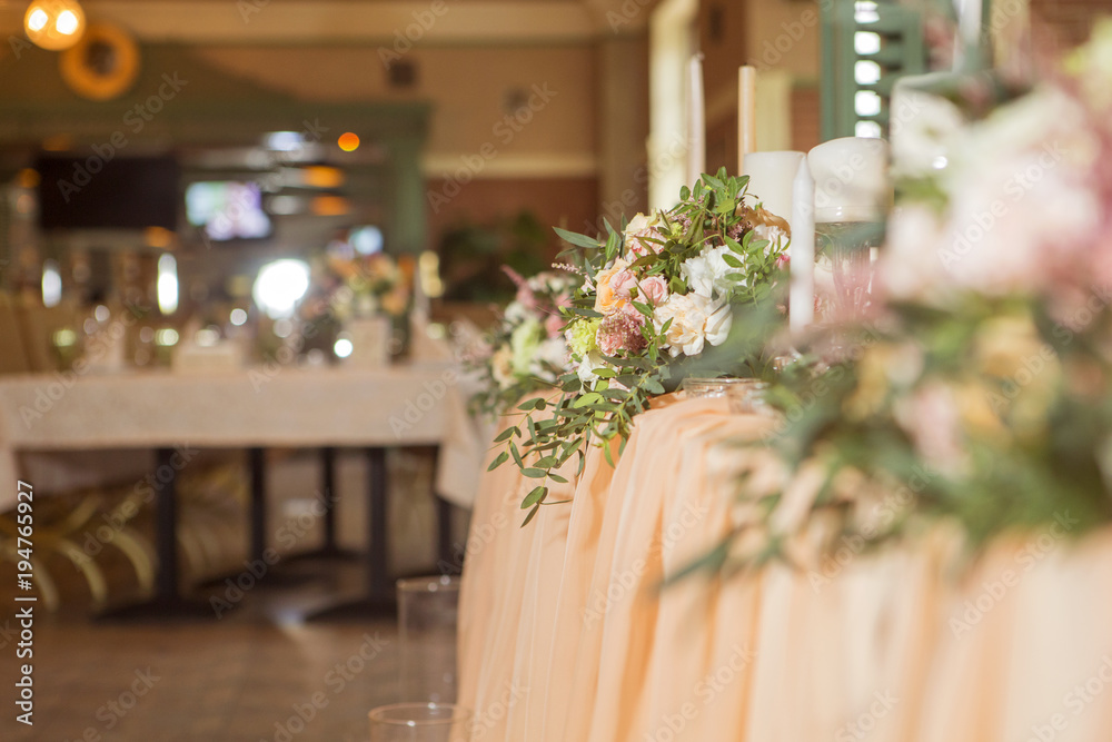 Wedding table decor full of rose and eustoma flowers, candles and peach colored fabric. Luxury rich restaurant interior. Indoor. Copy space