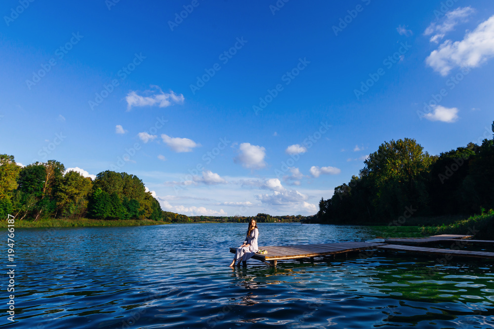 woman sitting on the pier  of the lake in beautiful sunny day on