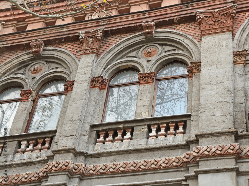 Obraz premium Clustered windows with relieving arches above them adorned with lion heads in round medallions in an old building on Soborna Street, Mykolaiv City, Ukraine