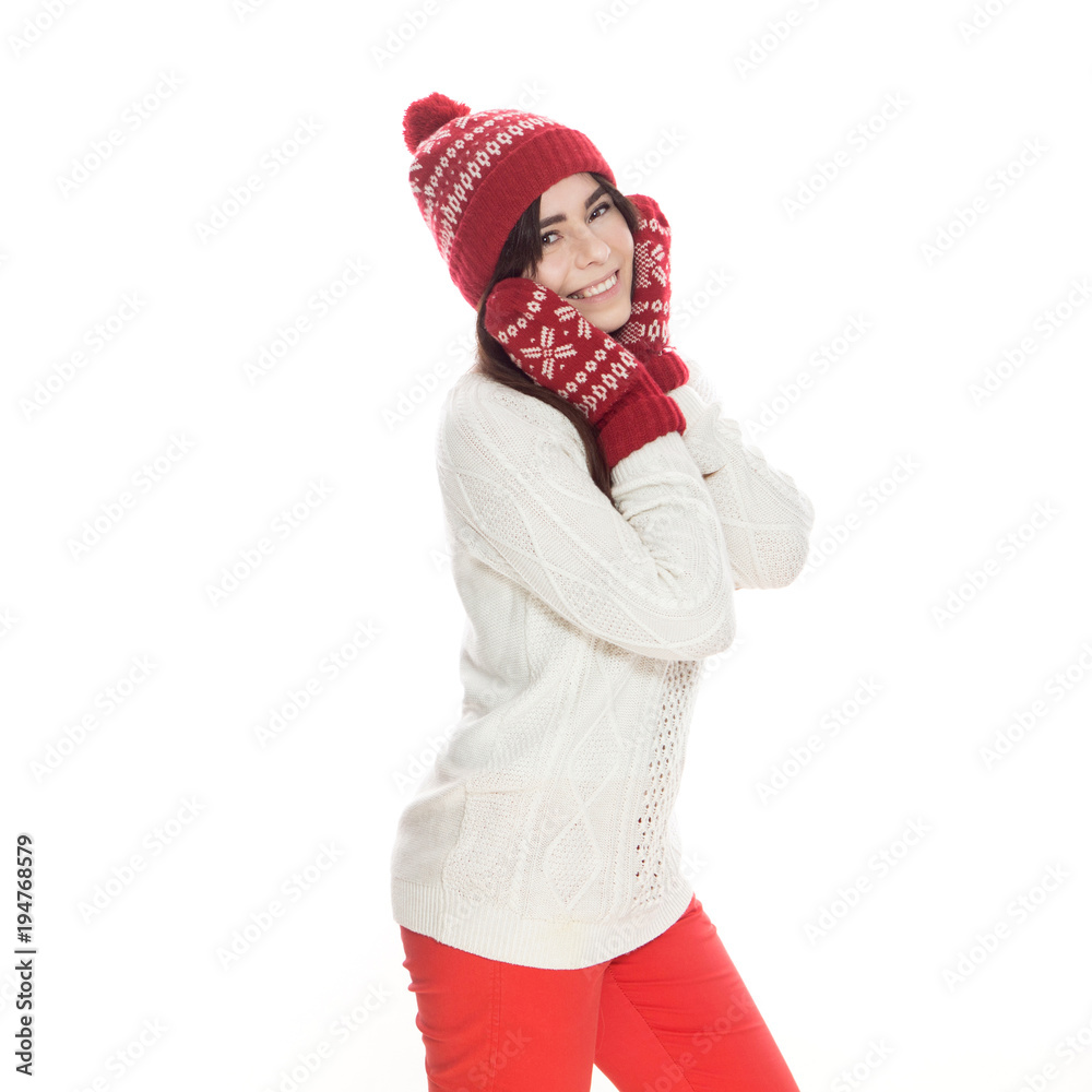 Cute teenage girl with long dark hair standing on a white background in white sweater, red gloves, trousers and hat. Emotional lifestyle portrait Cute teenage girl with long dark hair standing on a white background in white sweater, red gloves, trousers and hat. Emotional lifestyle portrait