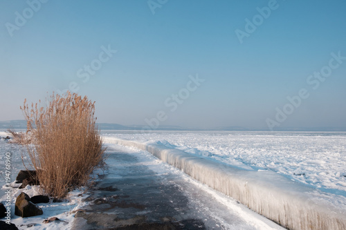icicles and ice at frozen lake Balaton  hills in background.