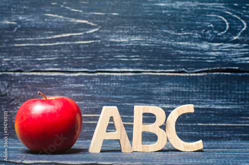 Red apple and letters ABC on a dark background of a school board. The concept of primary education. Apple for the teacher. Sadik, school, college, university, educational institution. Alphabet. photo