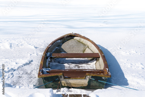 Old rowing boat in the frozen lake on a sunny winter day, concept metaphor for burn out, slow down and standstill in the business career or in private life, copy space
