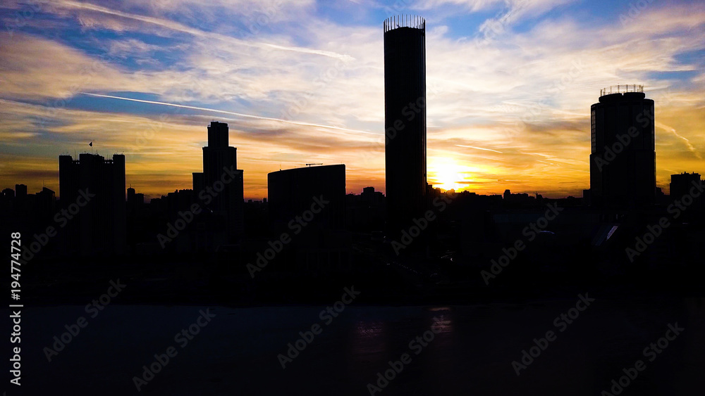 Aerial view on beautiful colorful dramatic sunset sky over silhouette of the city. Clip. City silhouettes at sunset with skyscrapers background. Sunset in town with business centres background