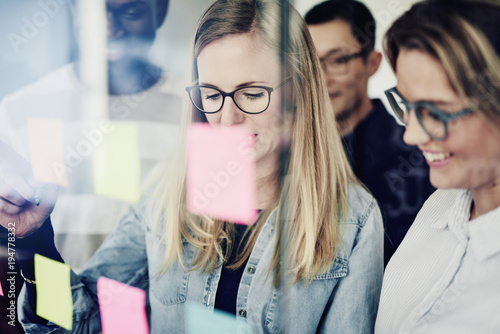 Diverse businesspeople brainstorming on a glass wall in an office