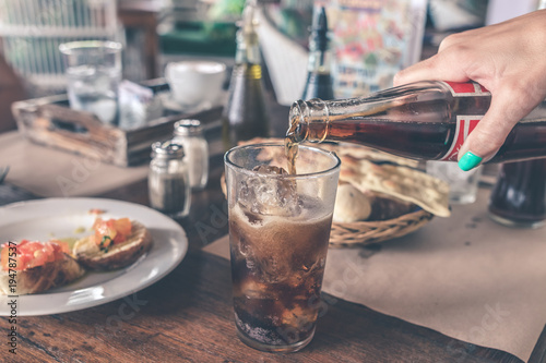 Pouring Cola with ice cubes. Cola drink with Ice and bubbles. Water drops on glass. Soda closeup. Restaurant.