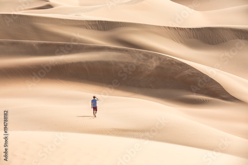 Young causasian male tourist in shorts hiking in giant Liwa desert dunes. Abu Dhabi  UAE.