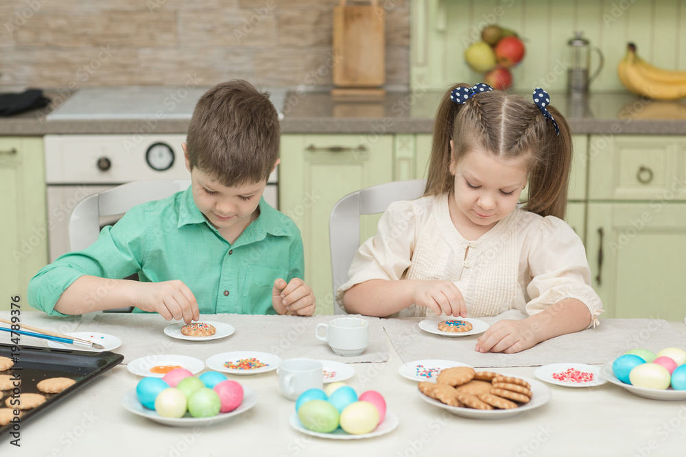 Cute children decorate cookies at a table in the home kitchen