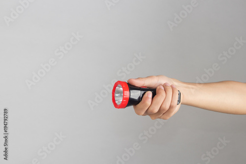 Hand holding flashlight on white background.