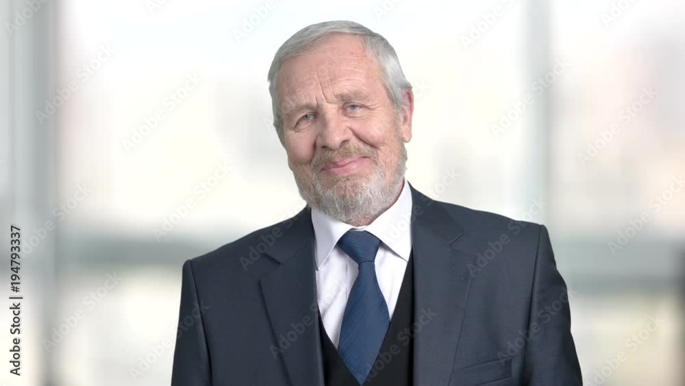 Happy senior businessman on blurred background. Smiling elderly man in business suit. Human facial expression of positivity. Happy senior businessman on blurred background. Smiling elderly man in business suit. Human facial expression of positivity.