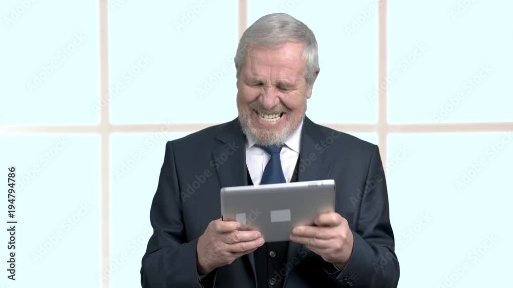 Aged man in business suit with pc tablet. Funny elderly businessman playing on digital tablet, window background. Aged man in business suit with pc tablet. Funny elderly businessman playing on digital tablet, window background.
