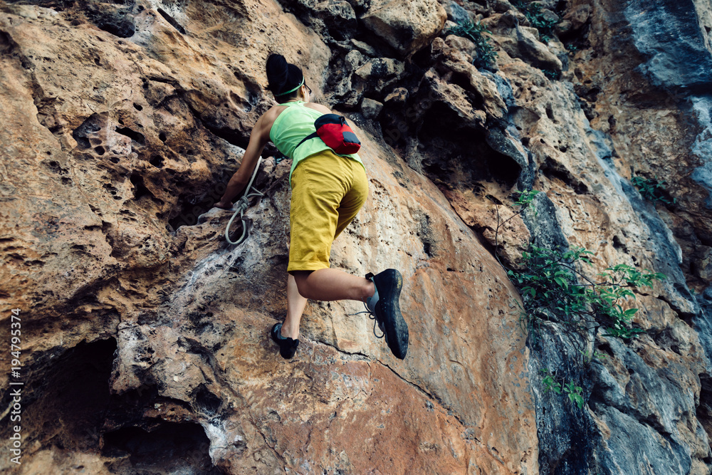 female rock climber climbing on steep cliff female rock climber climbing on steep cliff