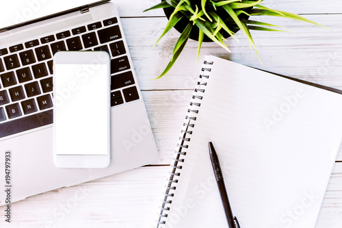 Top view of laptop and smartphone with blank screens on white office wooden desk table.Flat lay