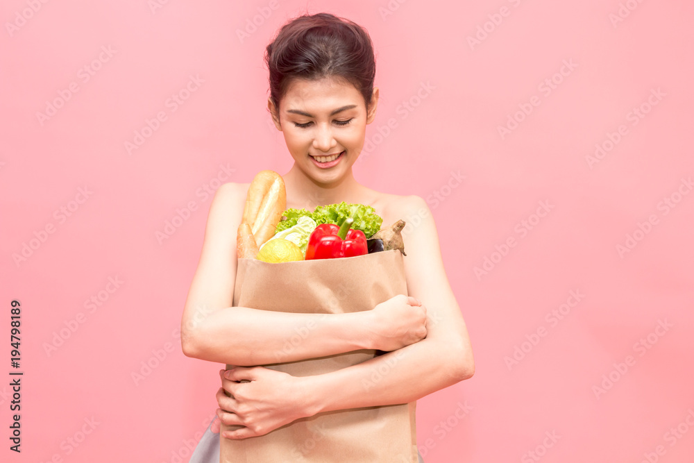 Woman holding shopping paper bag with fruit and vegetables diet healthy eating on pink background Woman holding shopping paper bag with fruit and vegetables diet healthy eating on pink background