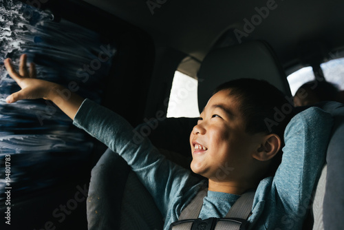 Little boy looking out car window while driving through car wash