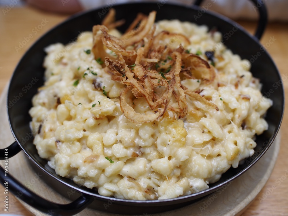 Rustikales - Käsespätzle mit Röstzwiebel serviert in der Pfanne Rustikales - Käsespätzle mit Röstzwiebel serviert in der Pfanne