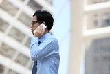 Portrait professional young Asian business man talking on phone for his job at outdoor street background.