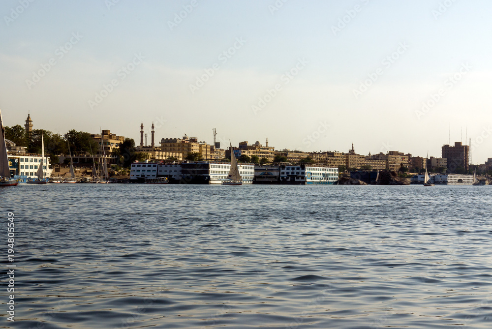 Cairo, Egypt February 18, 2017: Two Arab fishermen in a small boat typical of the Nile River, one paddling and the other crouching in the stern preparing the nets. In the background the city of Cairo
