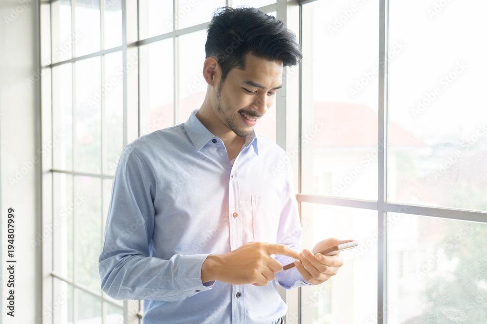 Business man wearing suit, looking smartphone. Open space loft office. Panoramic windows background. Business man wearing suit, looking smartphone. Open space loft office. Panoramic windows background.