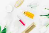Cosmetics, perfume, combs and tulips flowers on white background. Beauty blogger composition. Flat lay, top view
