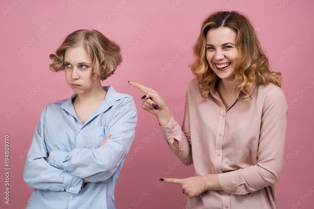 Two young girls pose for a Studio portrait on isolated background. The concept of trolling to be bullying and friendships Two young girls pose for a Studio portrait on isolated background. The concept of trolling to be bullying and friendships