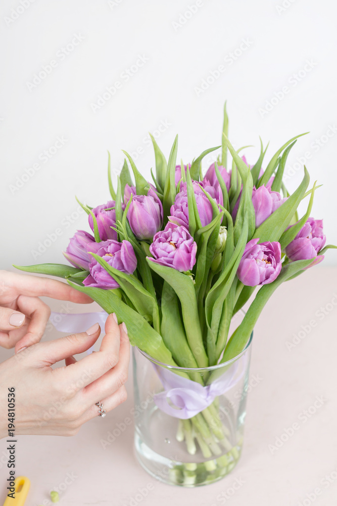 caring for a bouquet of flowers, step by step. Cut the stems and put in a vase. Young woman holding a beautiful bunch of violet tulips in her hands. Sunny spring morning.