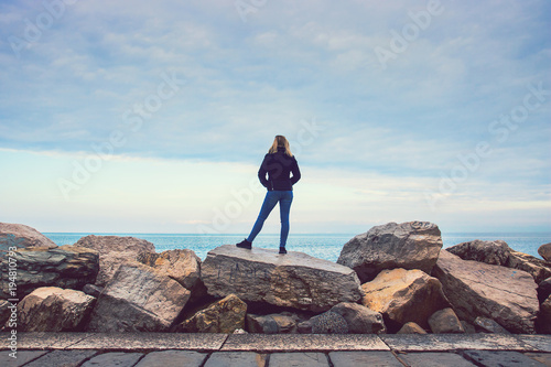 lonely woman on the rock at the seaside  blonde lady looking at the sea