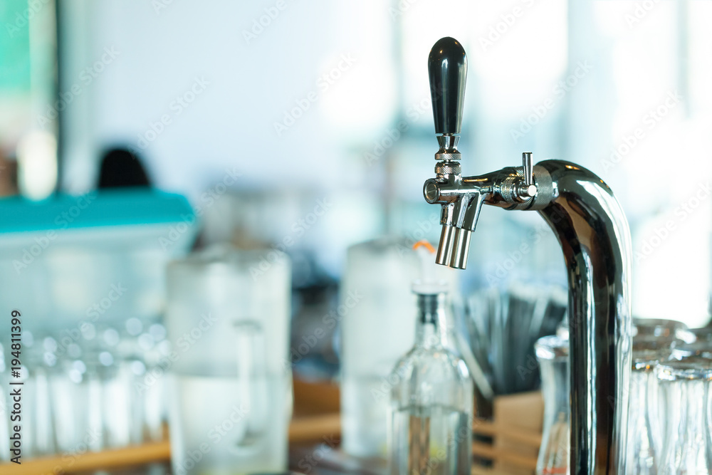 Shiny faucet for a classic draft beer in a restaurant with glasses on background Shiny faucet for a classic draft beer in a restaurant with glasses on background
