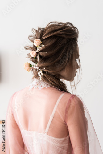 Beautiful bride's hairstyle from the back close-up. Hairstyle with flowers. Bride in a peignoir. Veil Peignoir. White background.